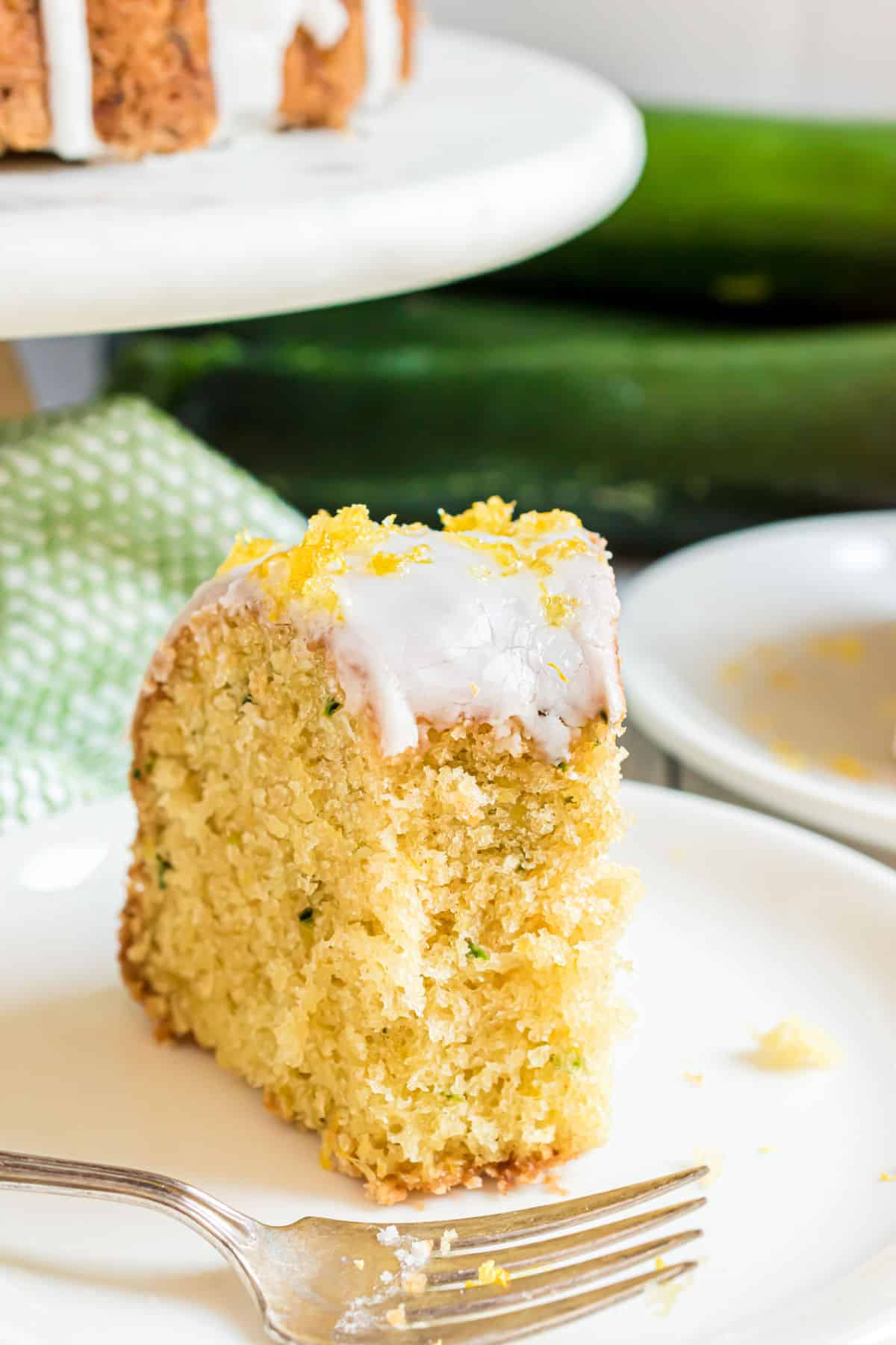 Slice of lemon zucchini cake with a bite taken out.