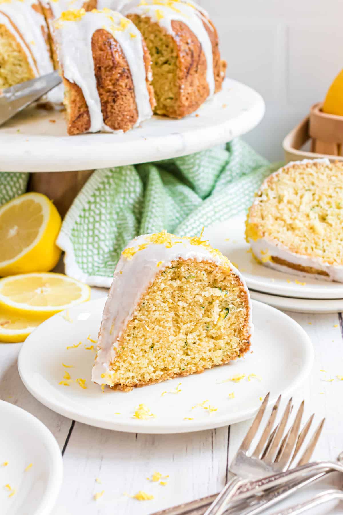 Slices of lemon zucchini cake on white plates.