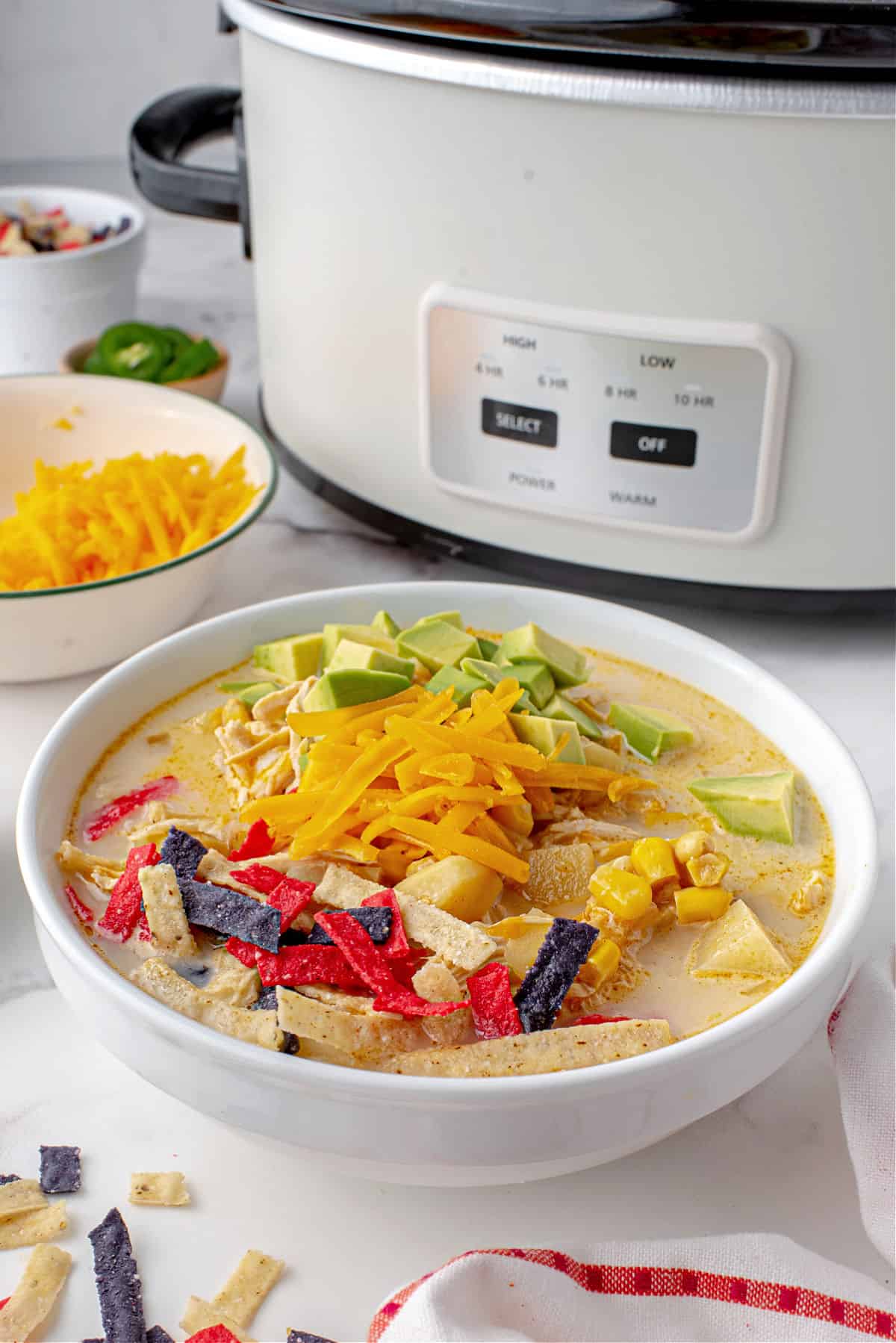 Southwest chicken chowder in a bowl with crockpot in back.