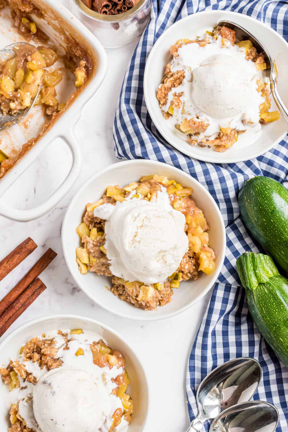 Three white bowls with zucchini crumble and vanilla ice cream.