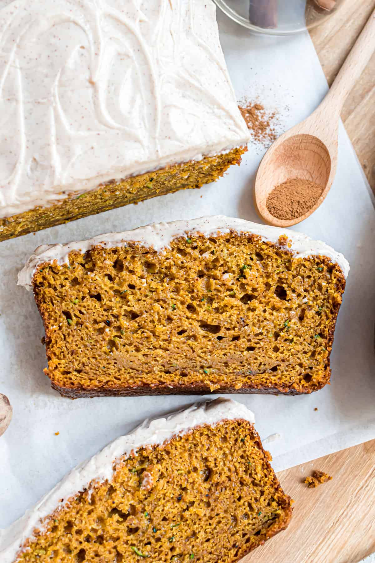 Slice of pumpkin zucchini bread topped with cream cheese frosting.