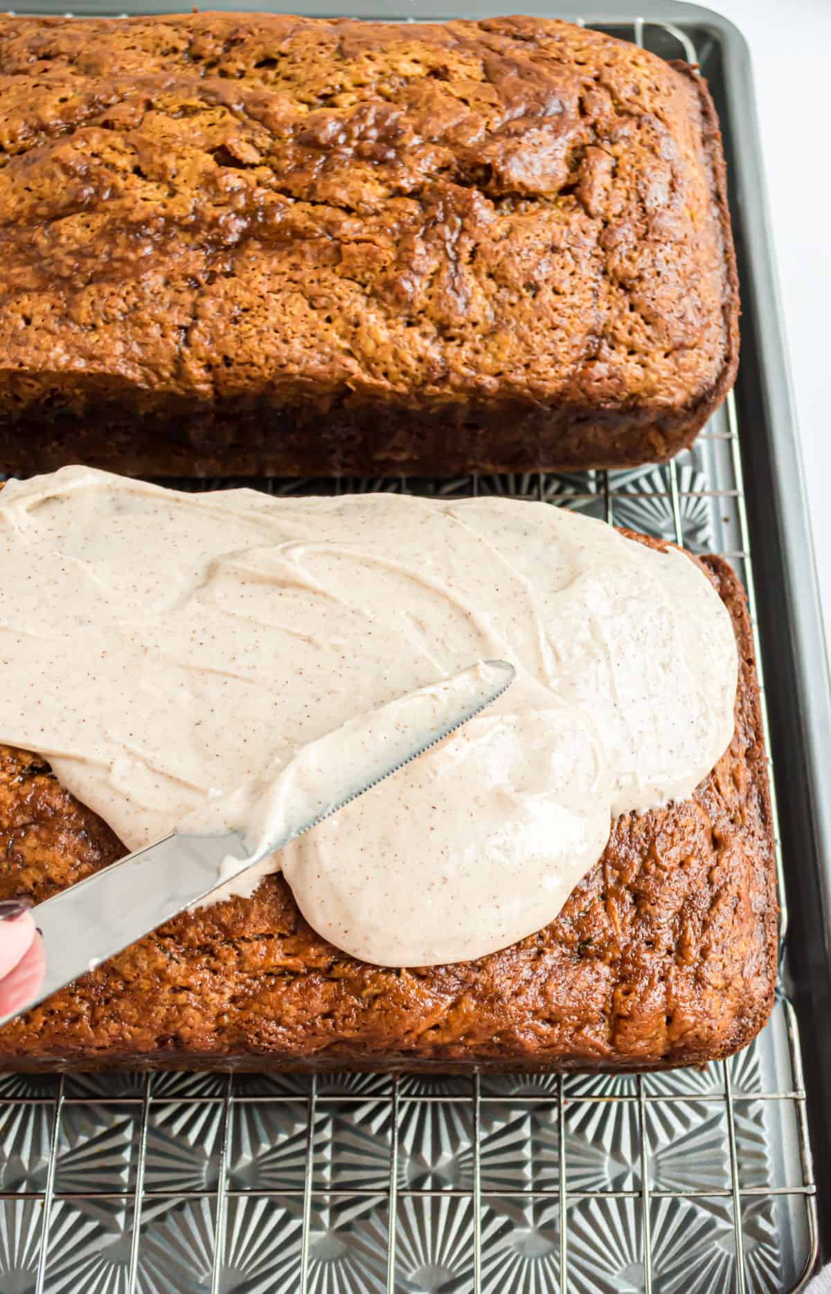 Cinnamon frosting being spread over cooled pumpkin bread.