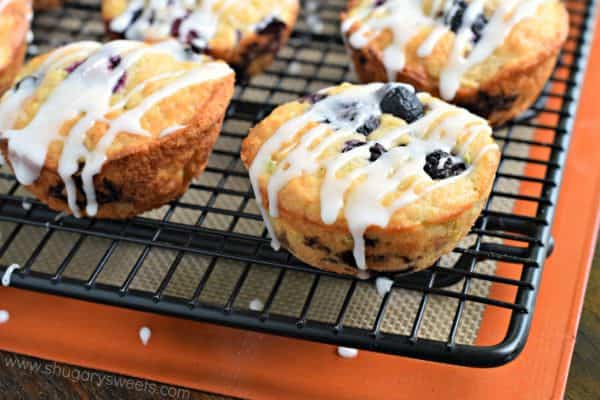 Zucchini muffins with bluerberries and lemon on a wire rack.