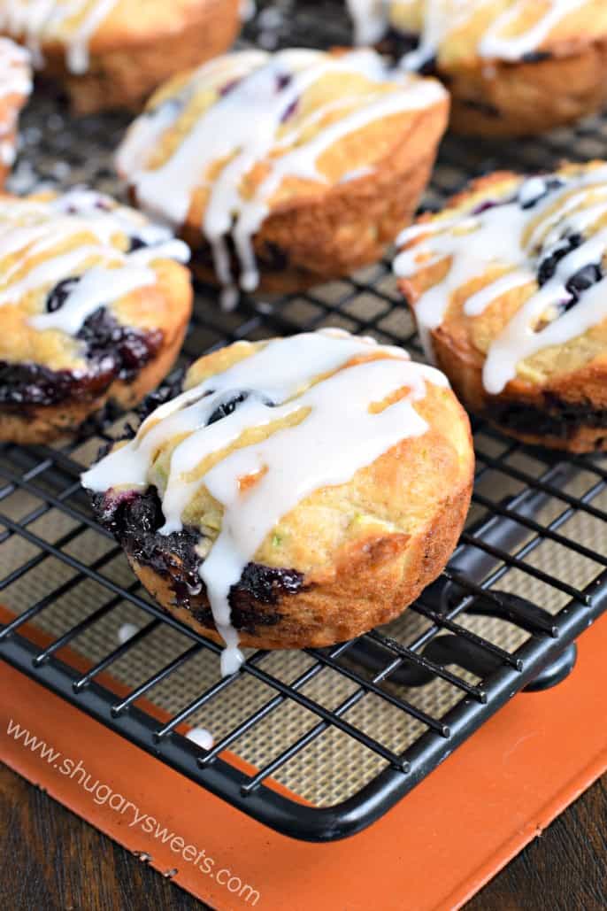 Blueberry zucchini muffins with lemon glaze on a wire rack.