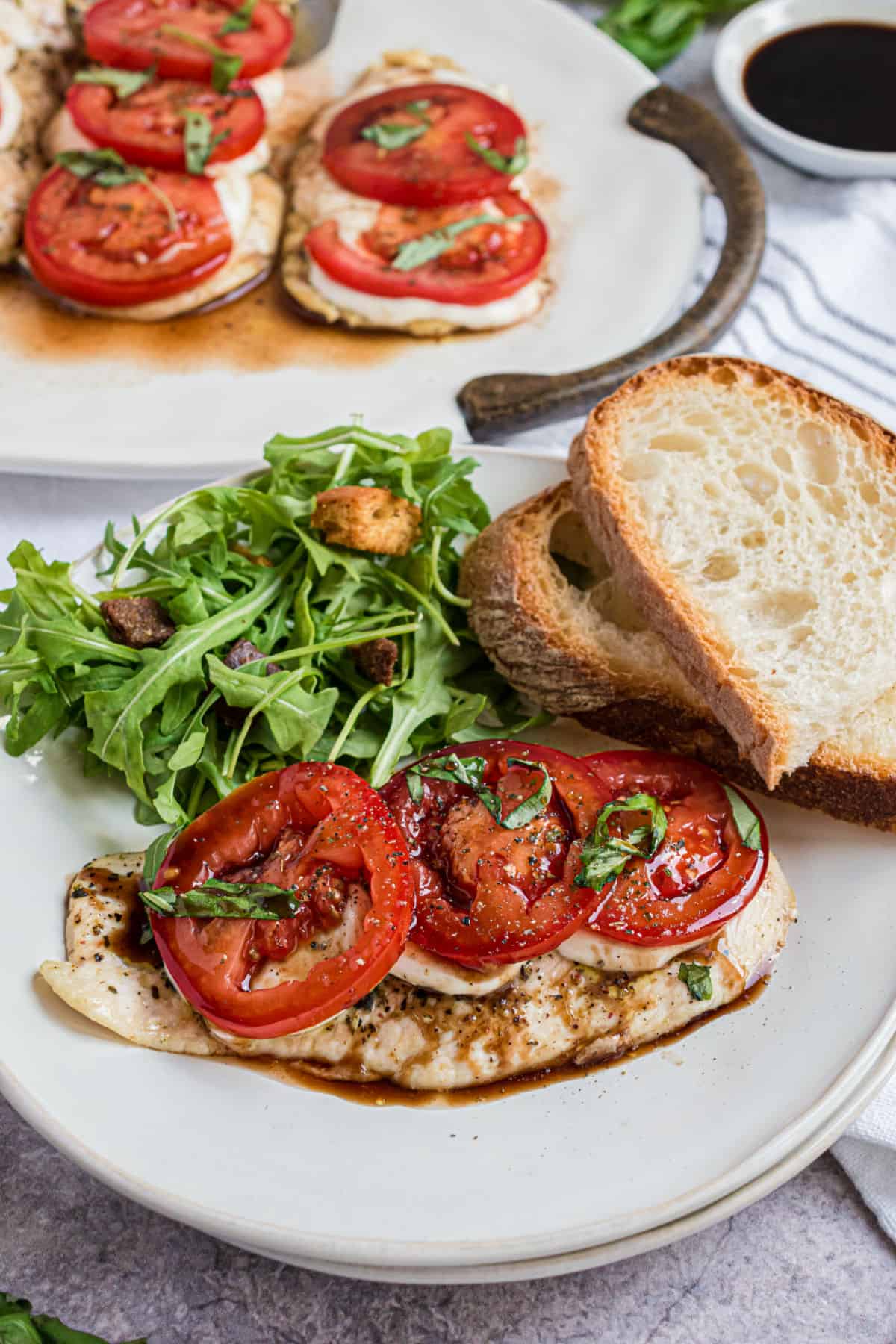 Chicken caprese served with a side salad and fresh bread slices.