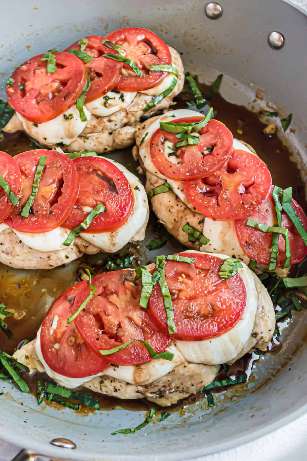 Skillet with chicken, tomatoes, cheese, and basil.