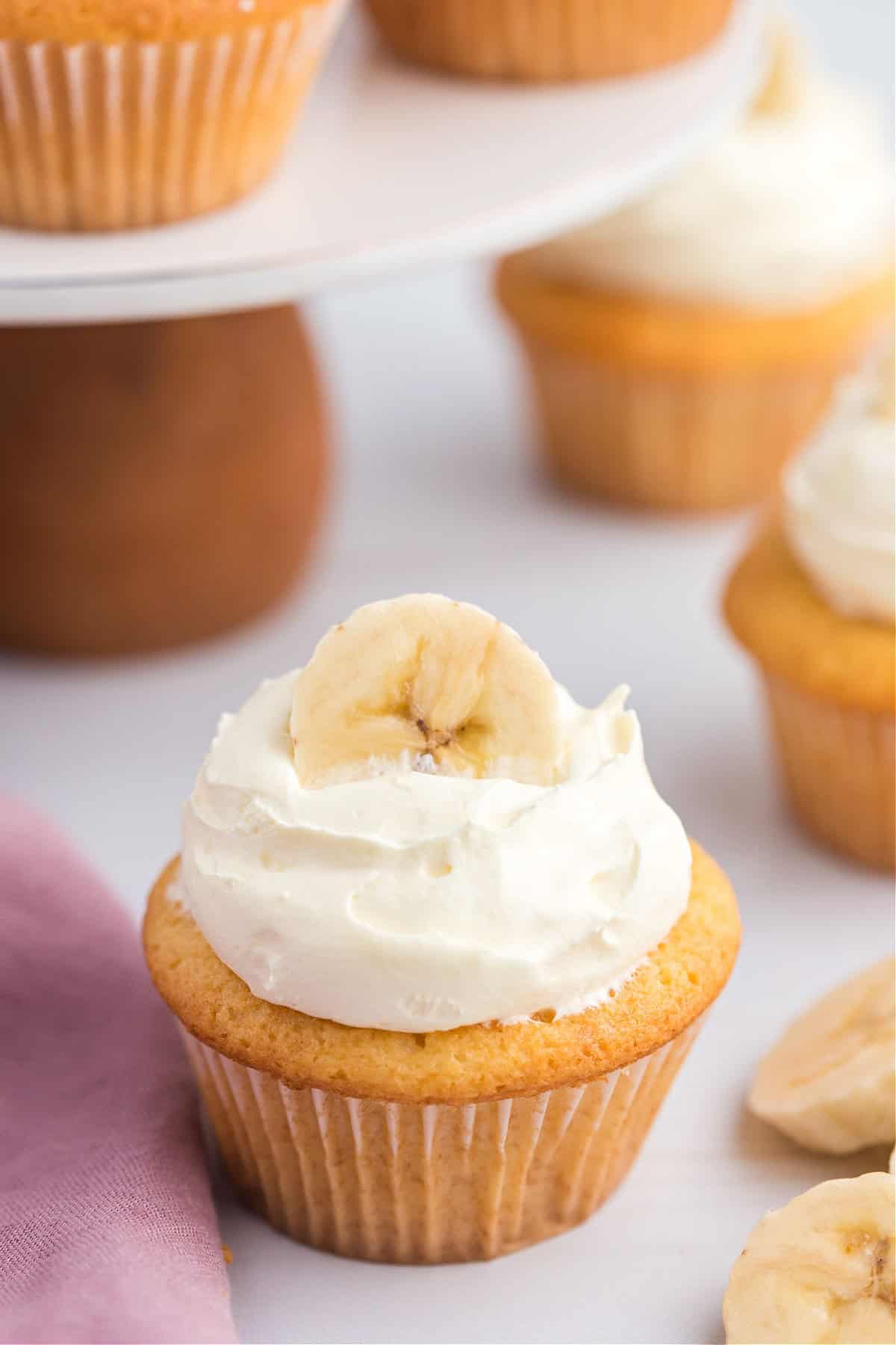 Banana pudding cupcakes with whipped topping and fresh bananas.