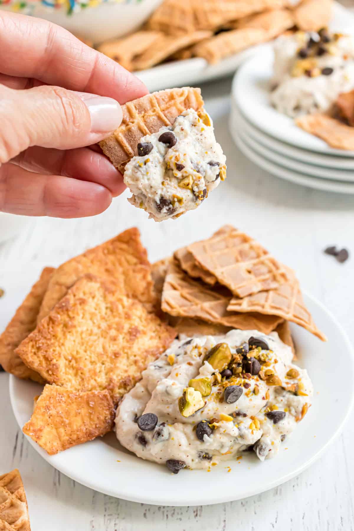 Cannoli dip served on a white plate with waffle cone pieces.