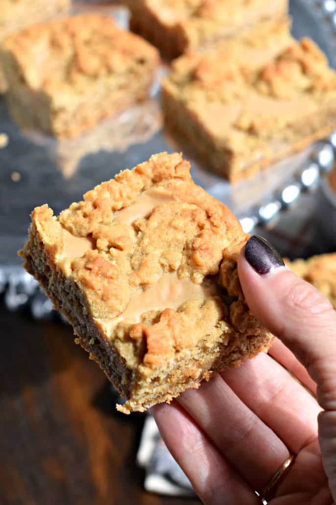 Oatmeal cookie bar with swirls of peanut butter held up close to camera.