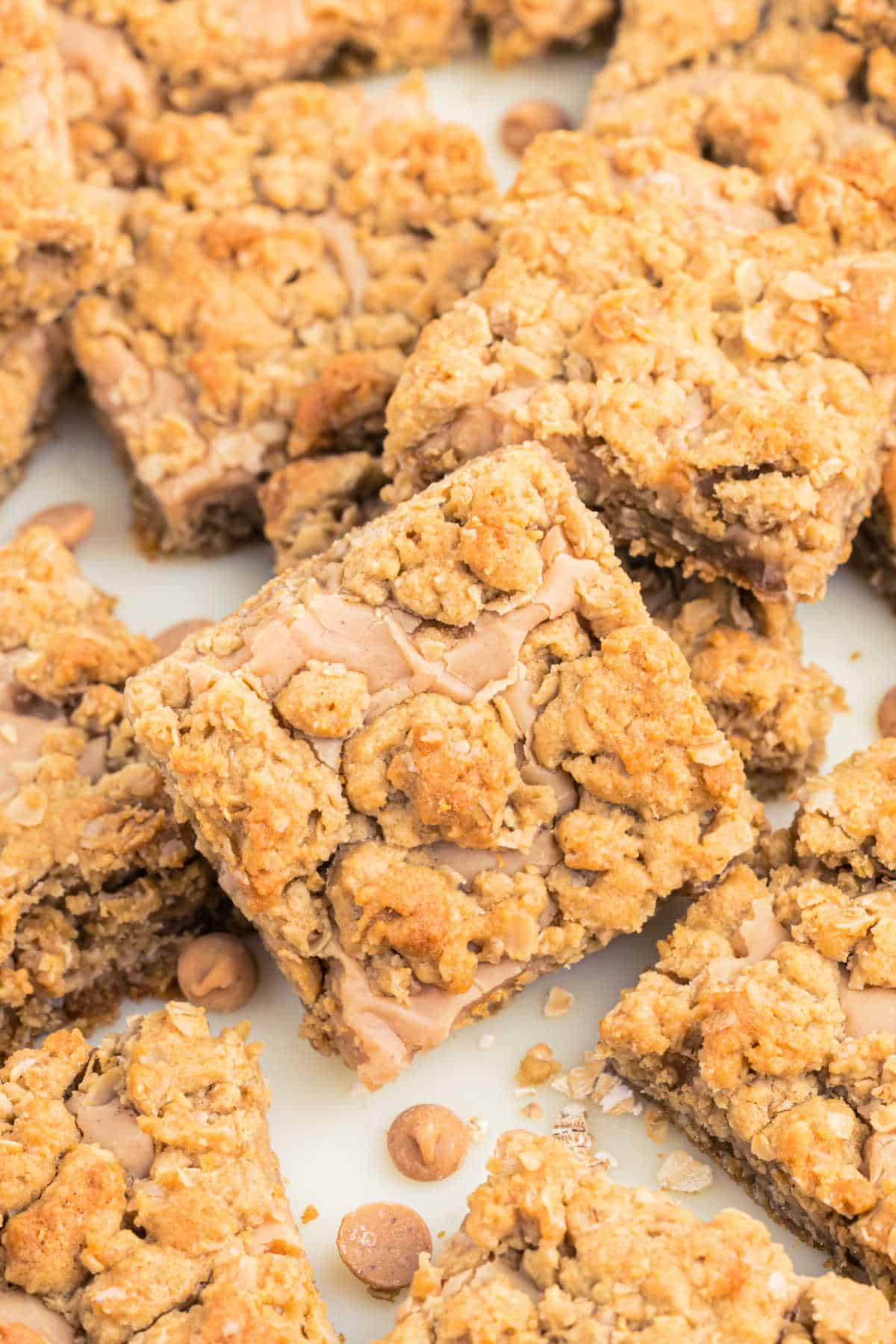 Close-up of oatmeal cookie bars with a crumbly topping and light brown filling, garnished with butterscotch chips—these peanut butter revel bars are an irresistible treat.