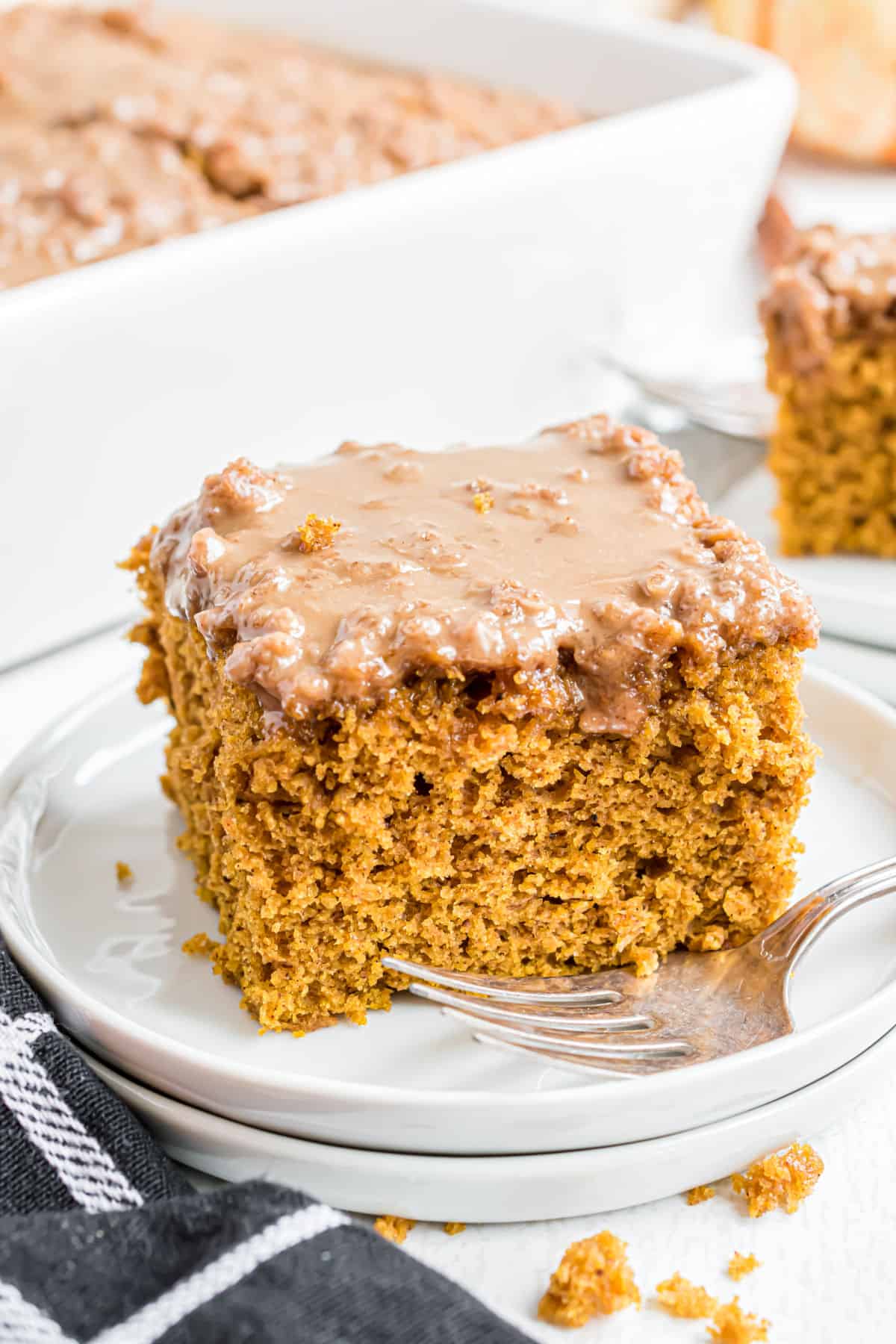 Slice of pumpkin coffee cake on a stack of white plates.