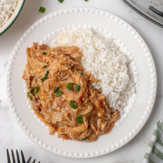 Bourbon chicken on a white place with rice.