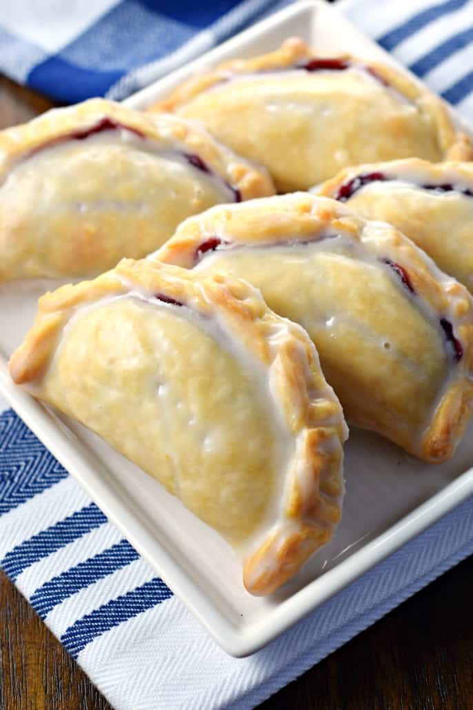 Blueberry Hand Pies lined up on a square white dessert plate.