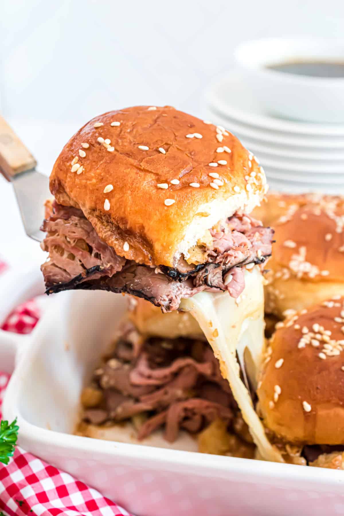 Roast beef slider being lifted out of baking dish.