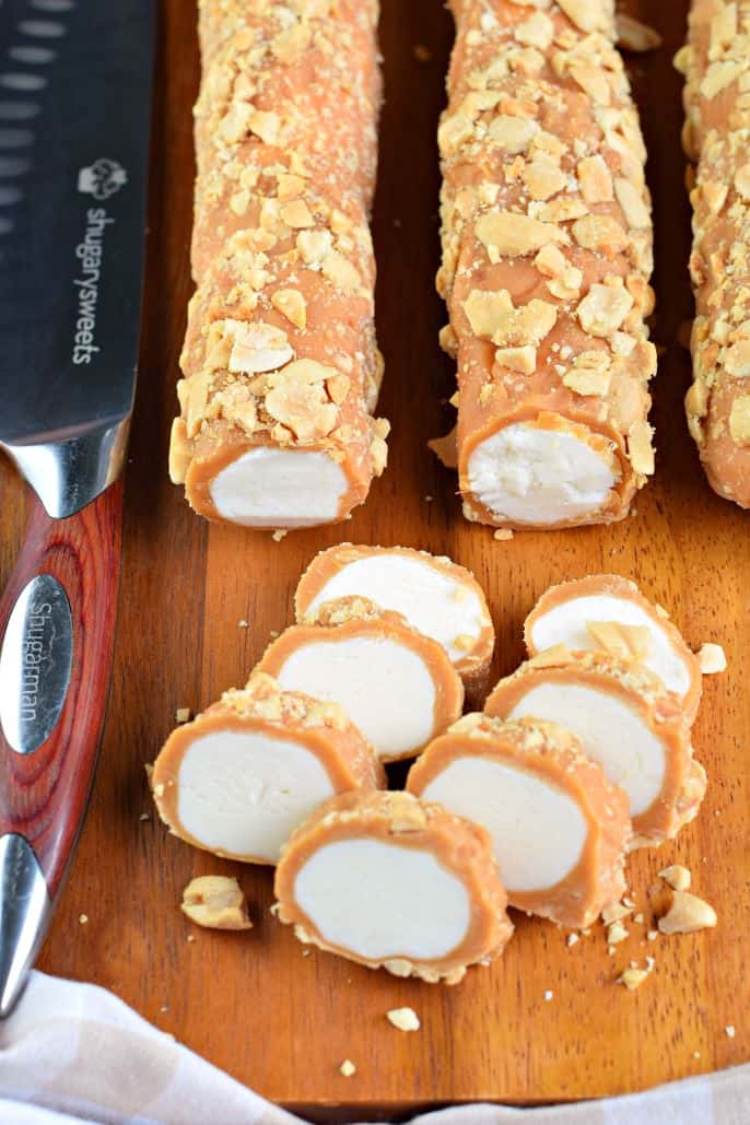 Salted nut roll candy on a wooden cutting board, with several pieces sliced.