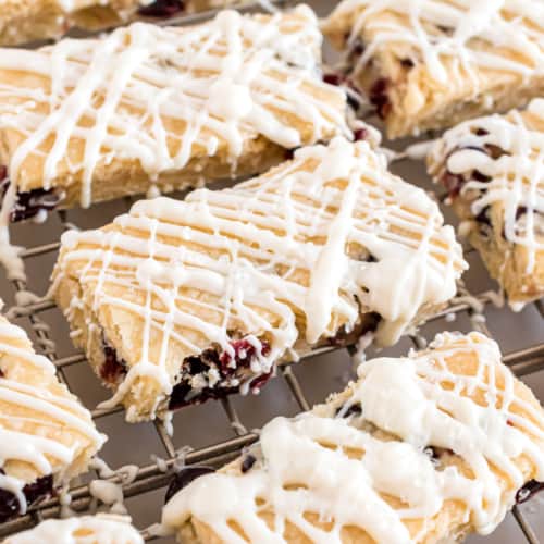 Shortbread cookie bars with cranberry and white chocolate on wire rack.