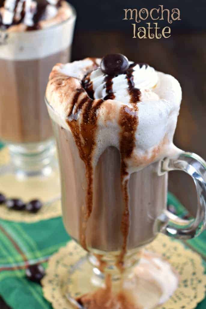 Clear glass mug with mocha latte and whipped cream dipping down the side of the glass.