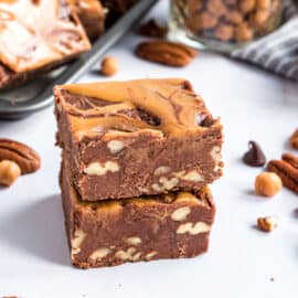 Two pieces of turtle fudge stacked on parchment paper.