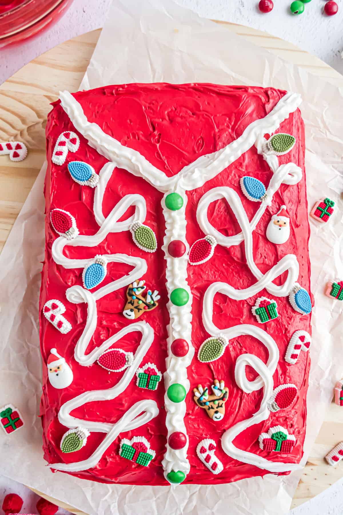 White cake with red frosting decorated to resemble an ugly Christmas sweater.