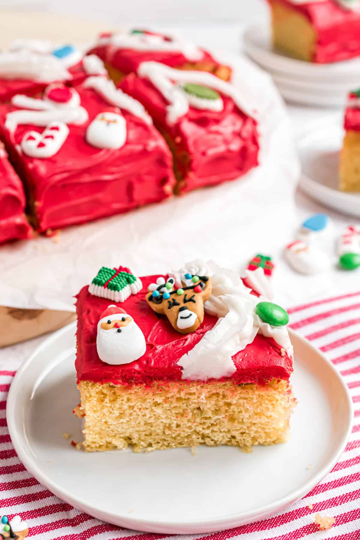 Slice of yellow cake with red frosting on a white plate.