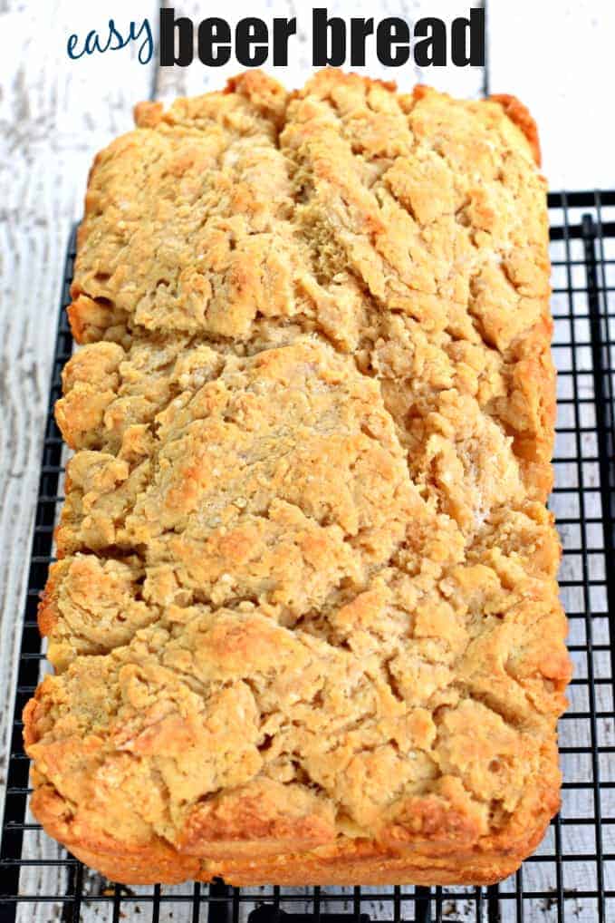 Loaf of beer bread on a black wire rack to cool.