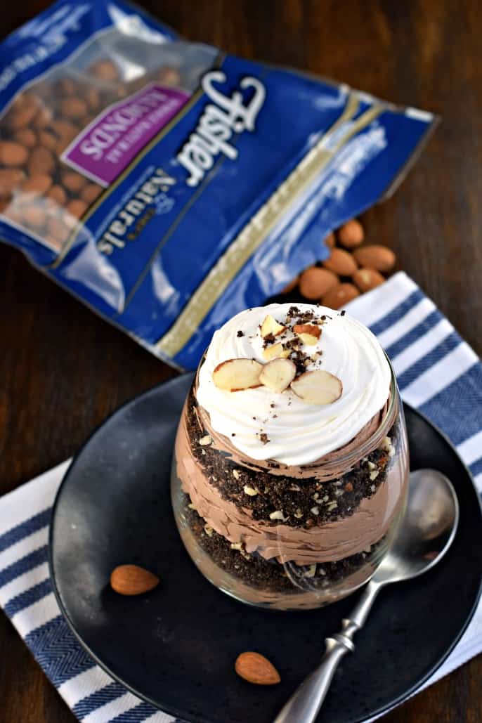 Parfait in a wine glass with cheesecake, cookie crumbs, and almonds.