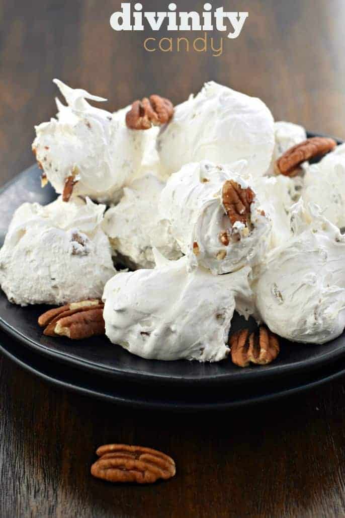 Pieces of divinity fudge candy on a black plate with pecans.