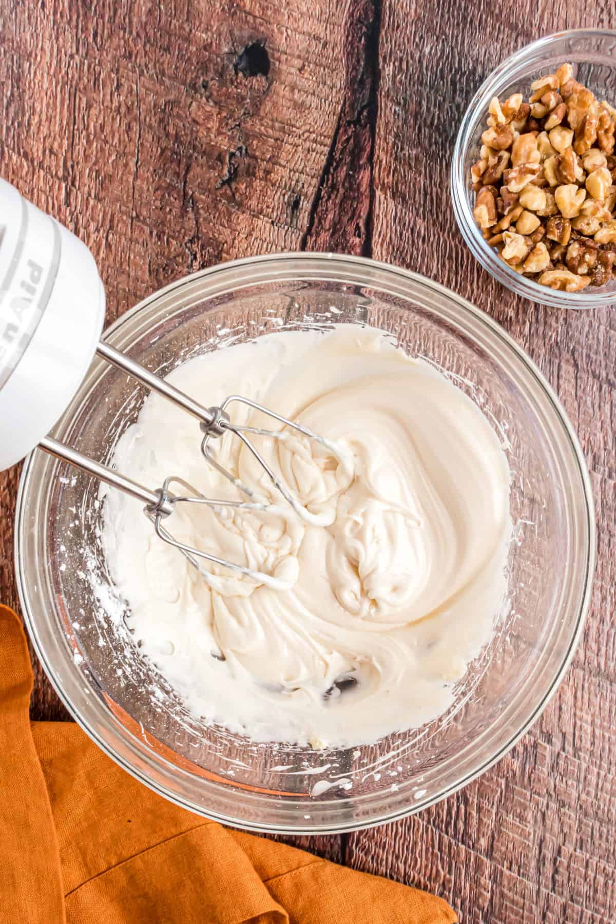 Cream cheese frosting in a clear glass bowl.