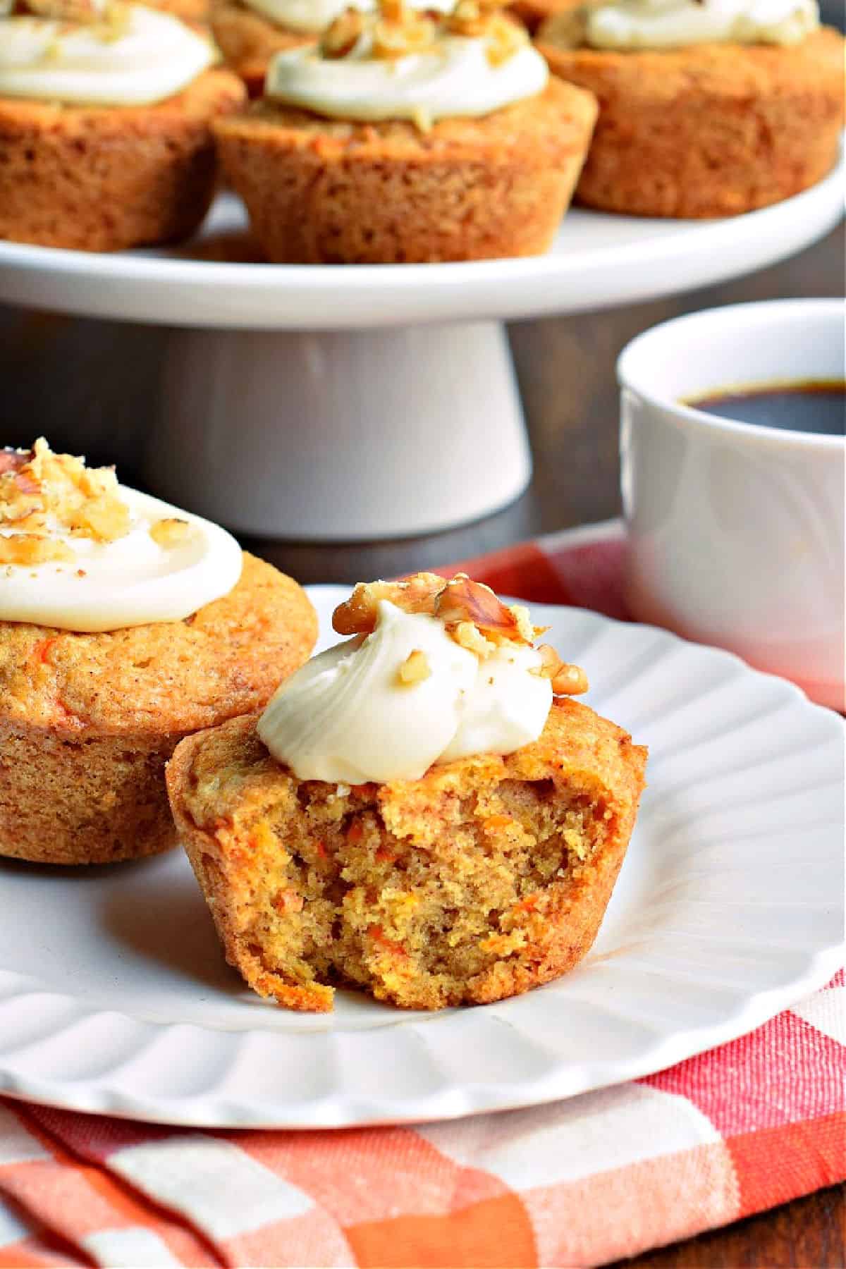 Carrot cake muffins with cream cheese frosting on a white plate.