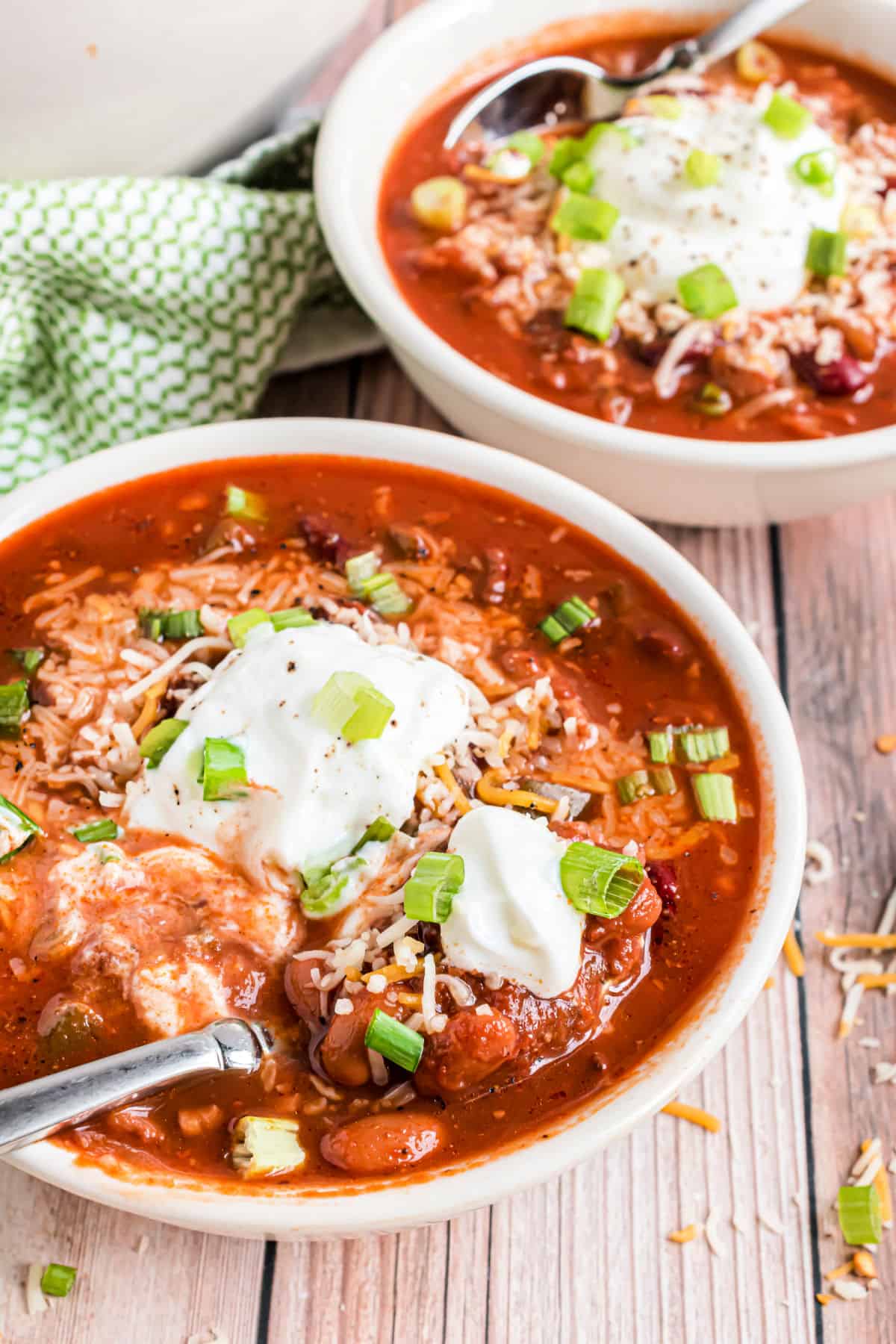Chili in white bowls topped with sour cream and green onion.