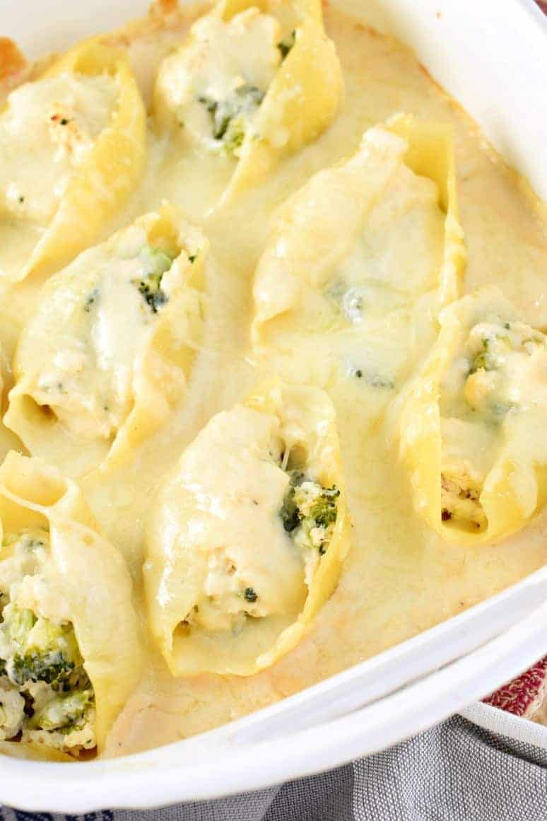 Stuffed shells with alfredo sauce and chicken in a baking dish.