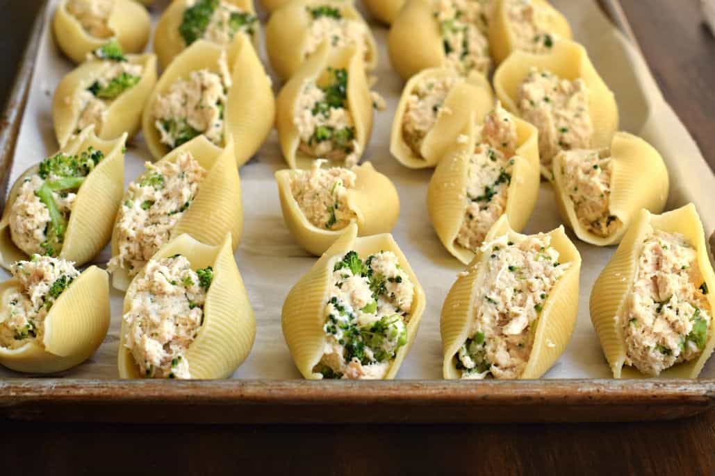 Large pasta shells stuffed with chicken and bacon on a baking sheet to freeze.
