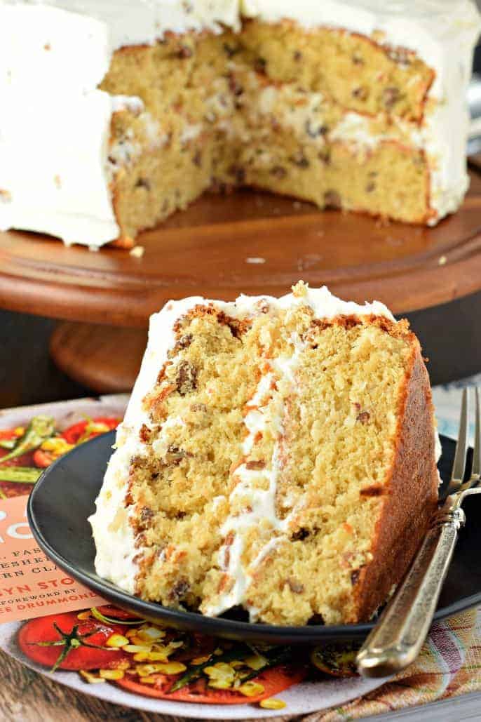 Slice of Italian cream layer cake on a black plate.