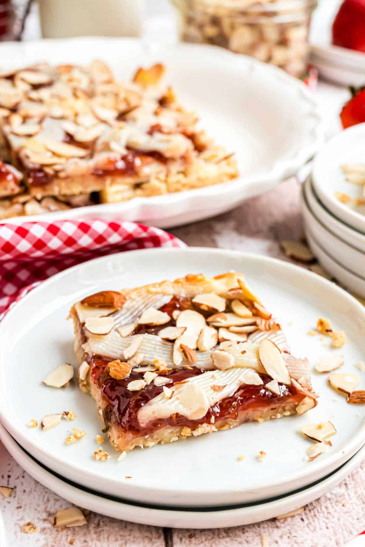 Slice of shortbread topped with strawberry and cheesecake on a white plate.