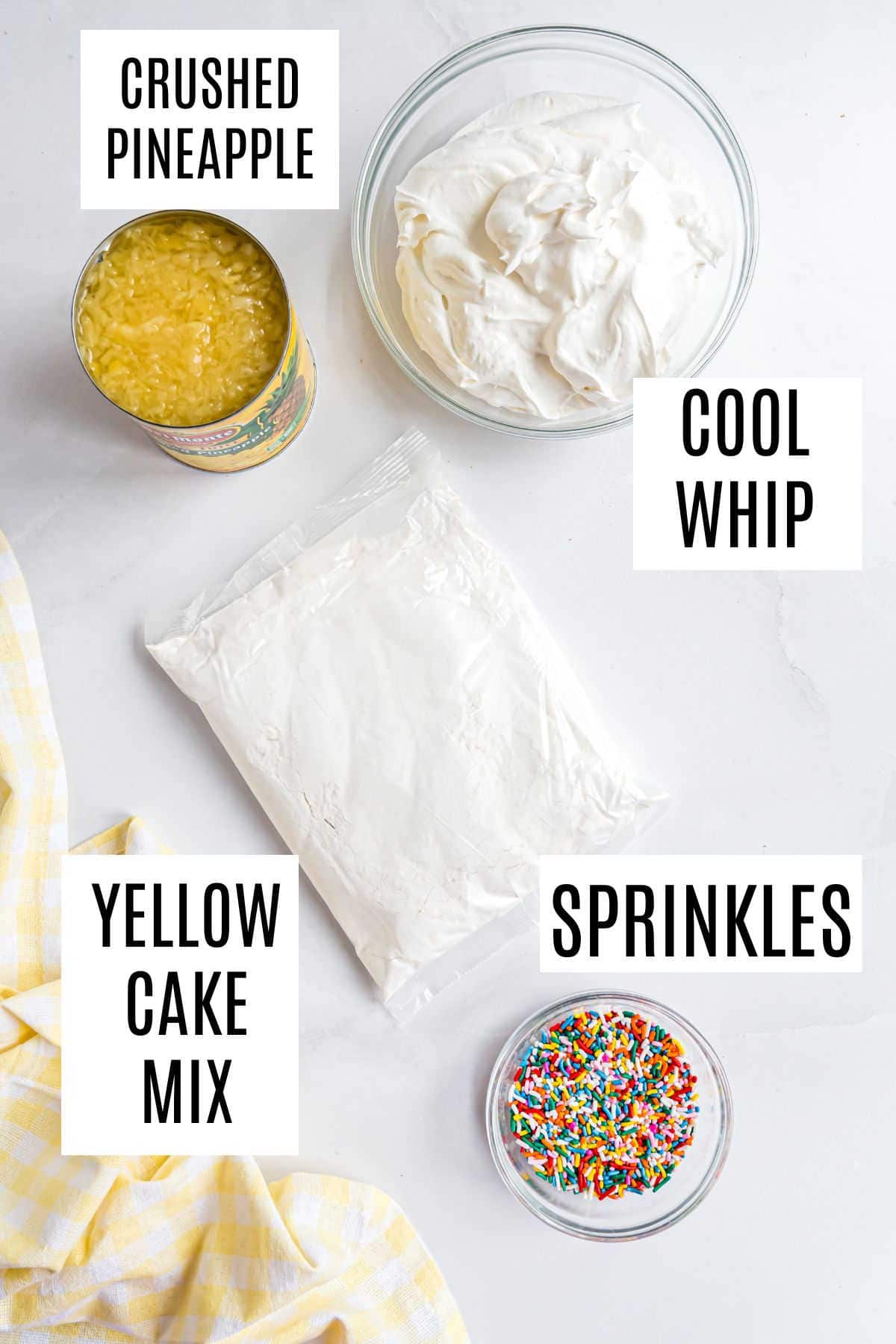 Crushed pineapple, Cool Whip, yellow cake mix, and sprinkles come together to create a delicious skinny pineapple cake on a white surface with a yellow cloth.