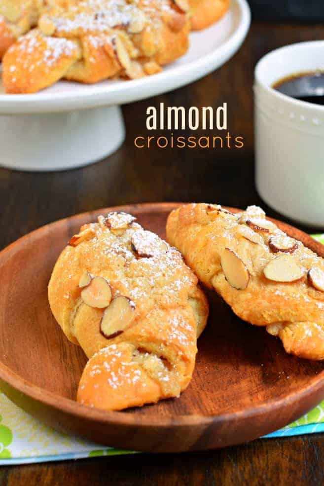 Almond croissants on a wooden serving plate.