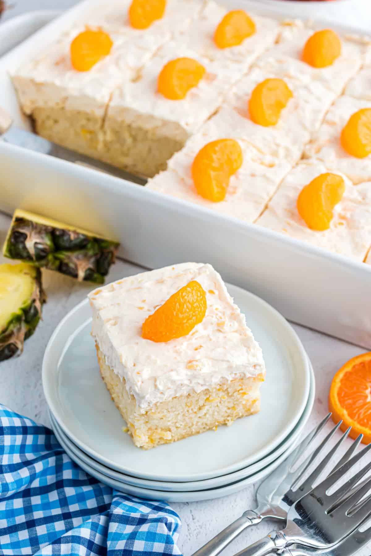 Pineapple orange cake on a stack of white plates.