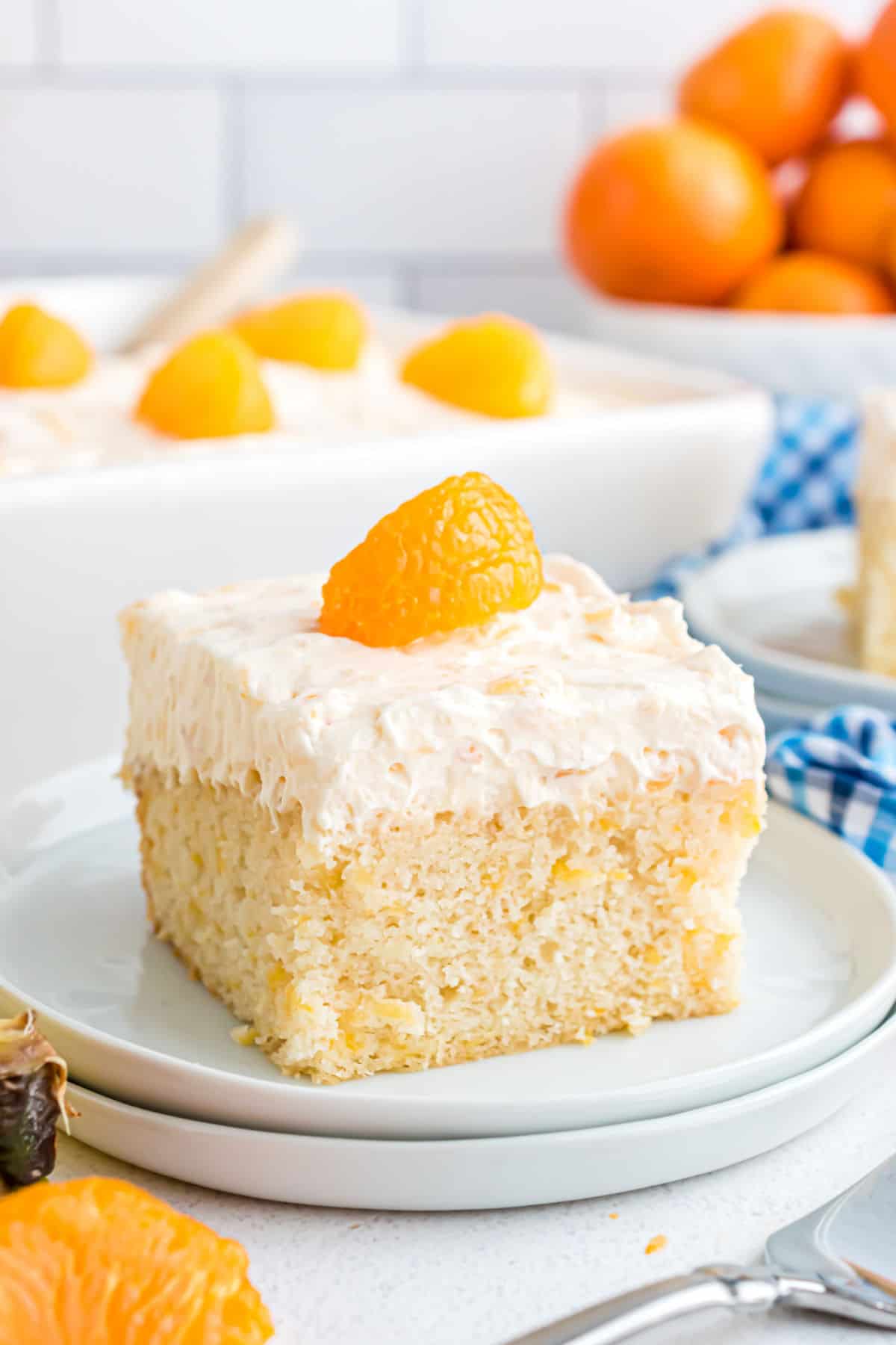 Slice of pineapple cake with whipped cream frosting and mandarin oranges.