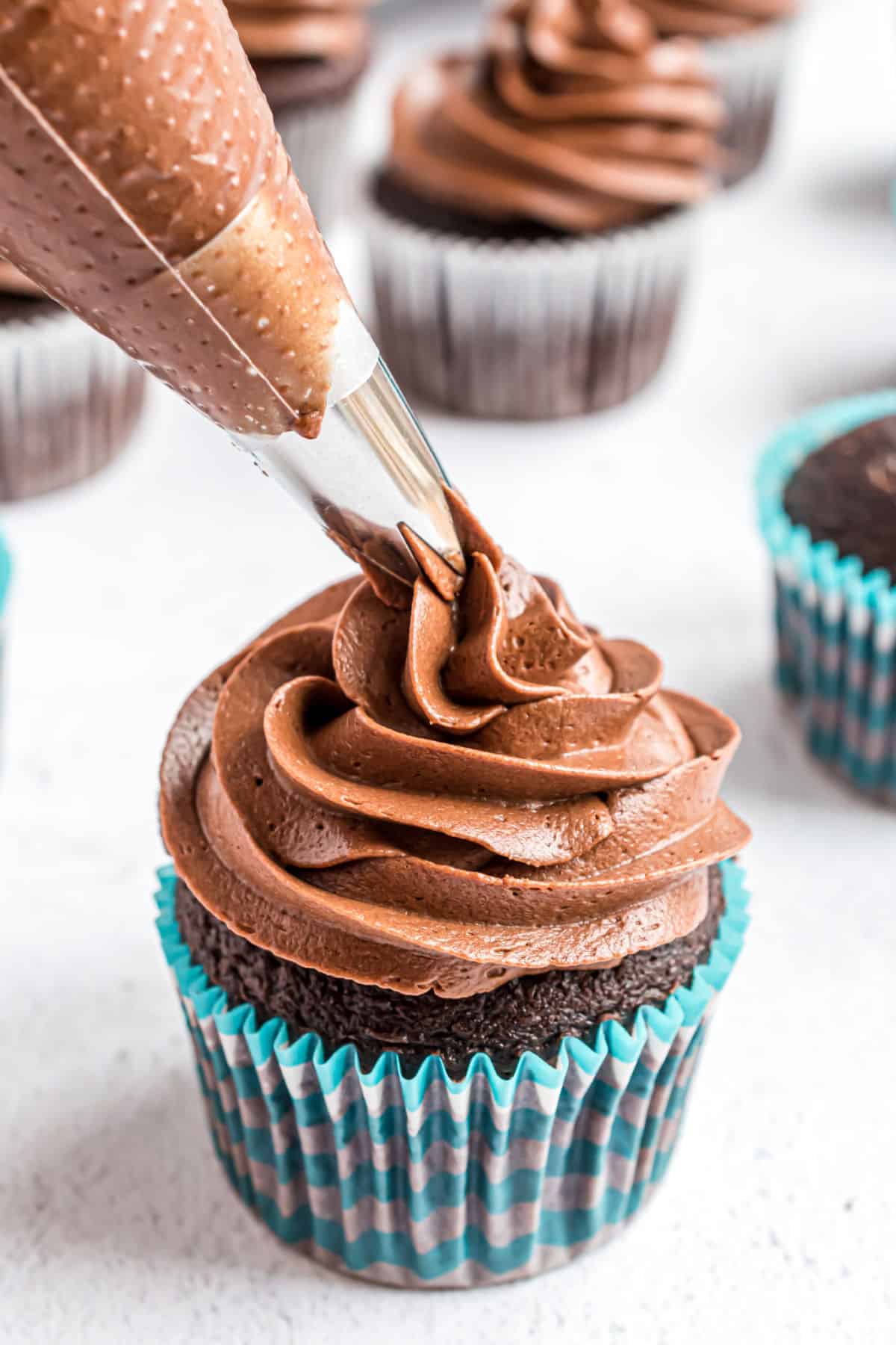 Chocolate cupcake with chocolate frosting being piped on top.