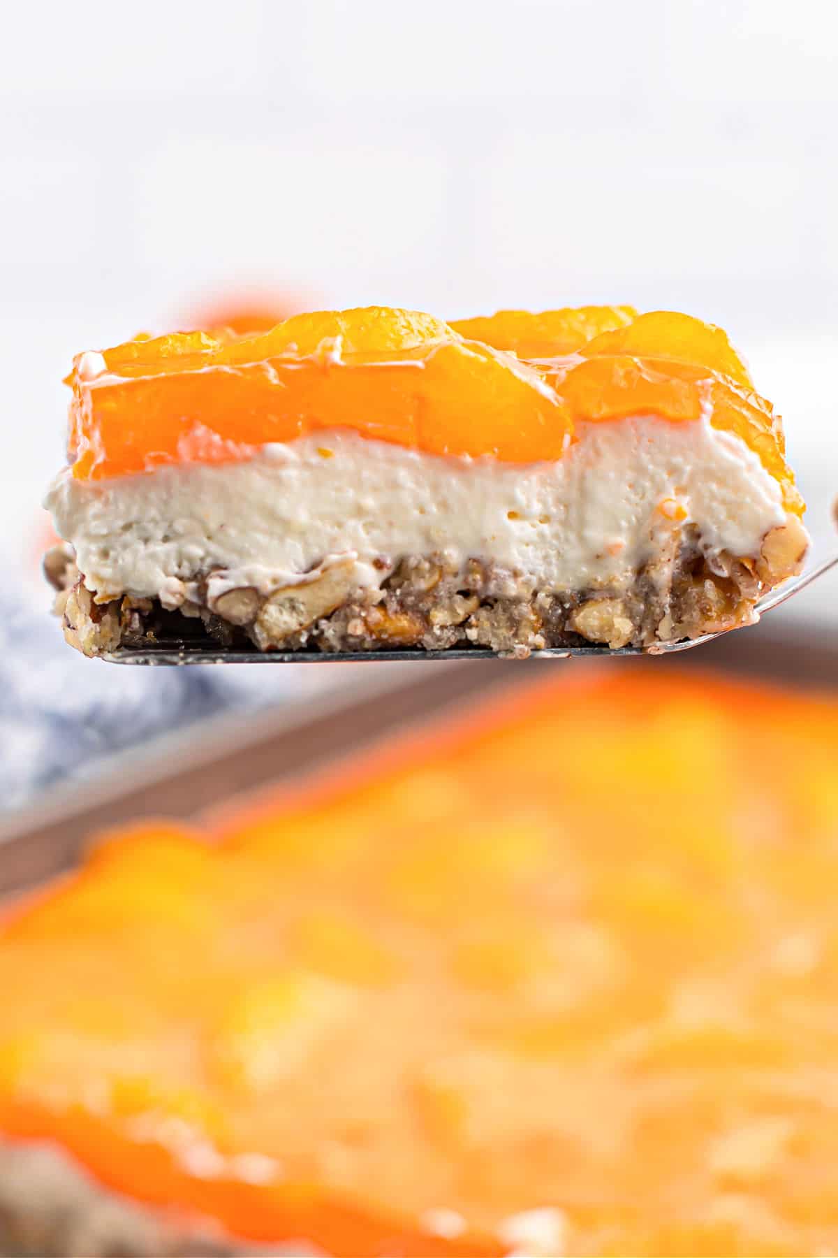 Slice of mandarin orange cheesecake bar being lifted out of baking dish.