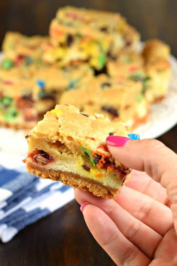 These M&M Cheesecake Bars have a sweet graham cracker crust, creamy cheesecake filling, and a chocolate chip cookie dough packed with M&M's on top!