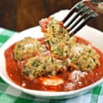 Zucchini meatballs with pasta sauce, one cut in half.