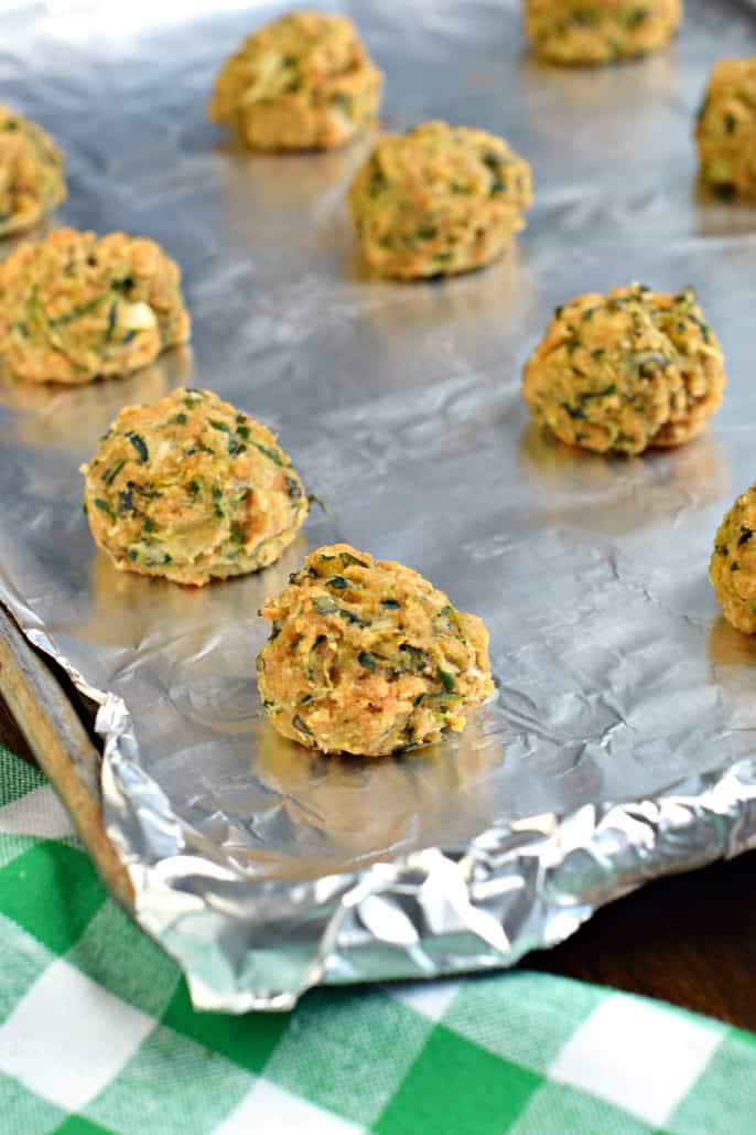 Zucchini meatballs on a foil lined baking sheet.