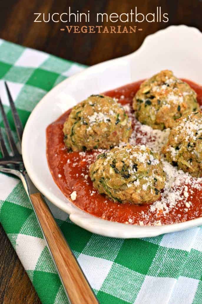 Meatless zucchini meatballs in a white bowl with marinara sauce and parmesan cheese.