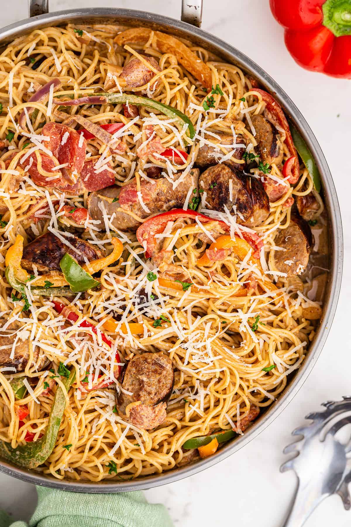 Cajun sausage pasta in a skillet topped with parmesan cheese.