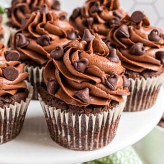 Chocolate cupcakes on a white cake platter.