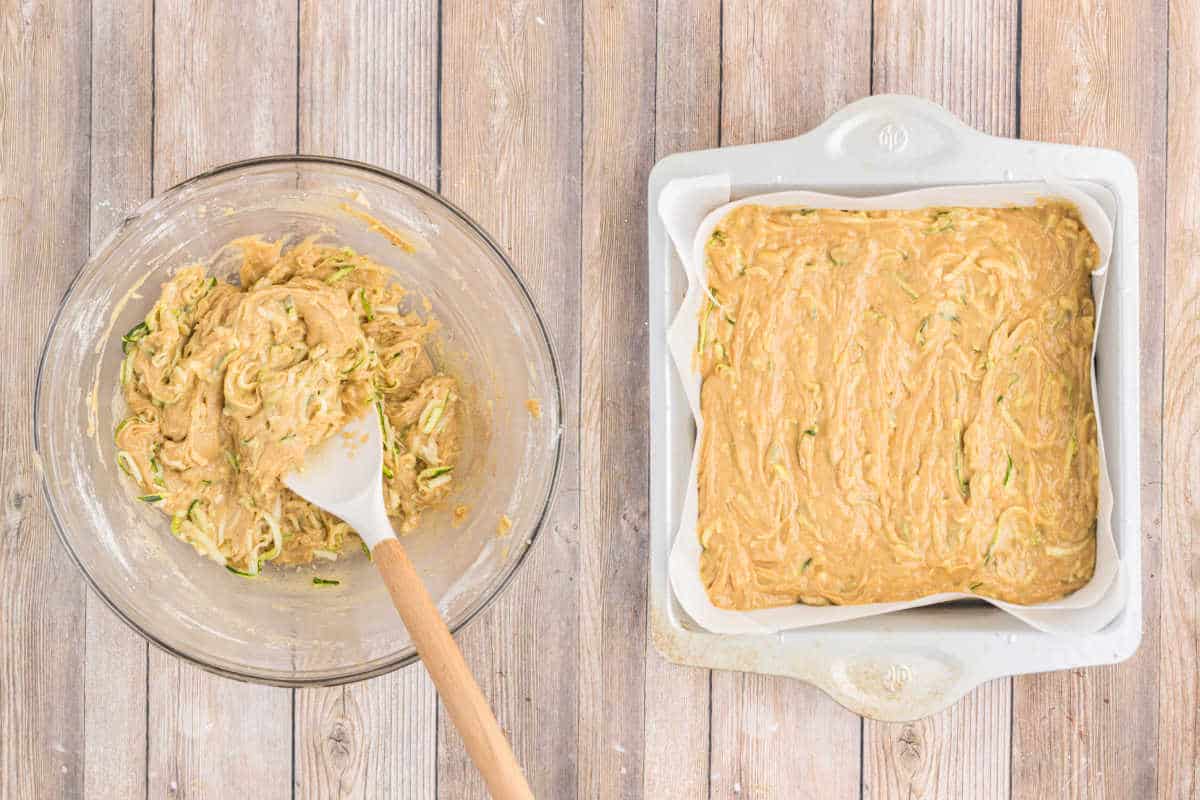 A bowl of zucchini bread batter and a baking pan filled with the same batter on a wooden surface, ready to be baked into delicious cinnamon frosted zucchini cake bars.