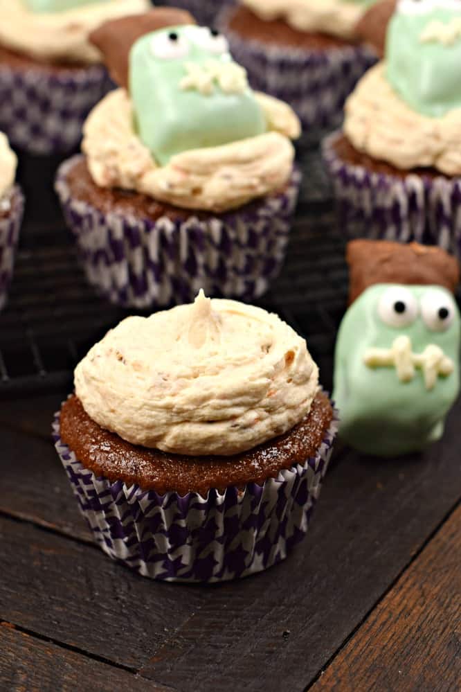 Undecorated chocolate cupcake with butterfinger frosting. Candy frankensteins in background.