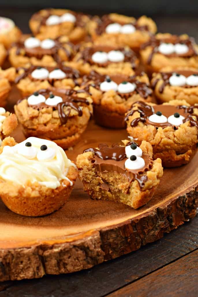 Peanut butter cookie cups with one bite removed showing Reese's filling.