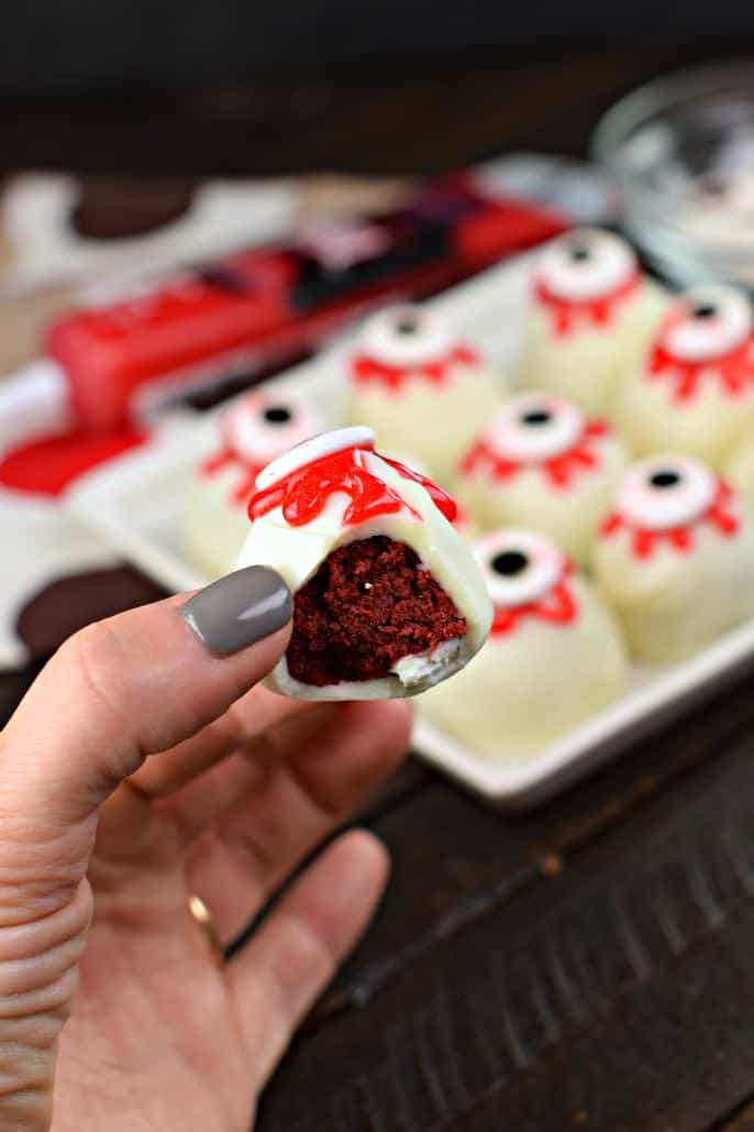 Red velvet cake ball with one bite removed.